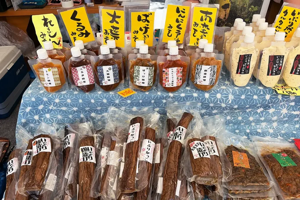 秋田の名産「いぶりがっこ」や、ずらりと並んだ色とりどりのパウチ入り味噌(レモン味噌、大葉味噌、にんにくラー油味噌など)。