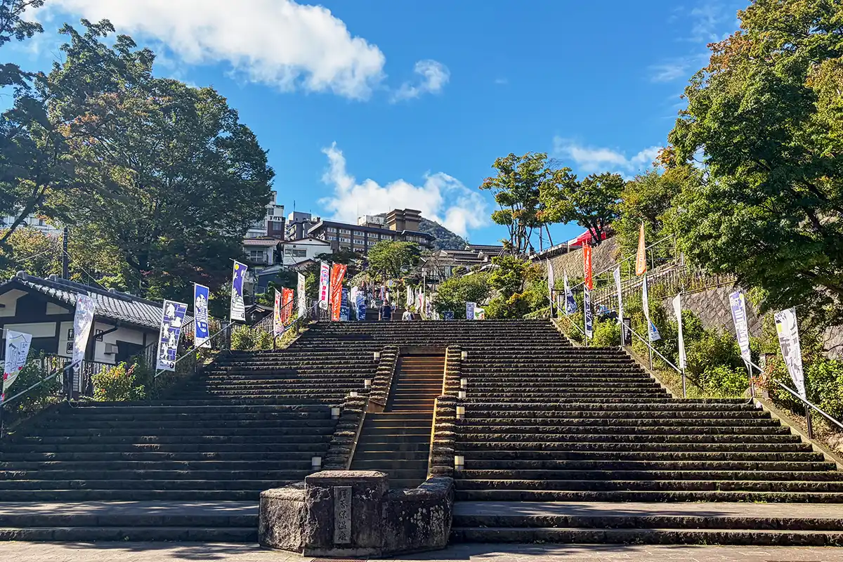 晴れた日の伊香保温泉石段街。青空の下、下から見上げた石段と色とりどりののぼり