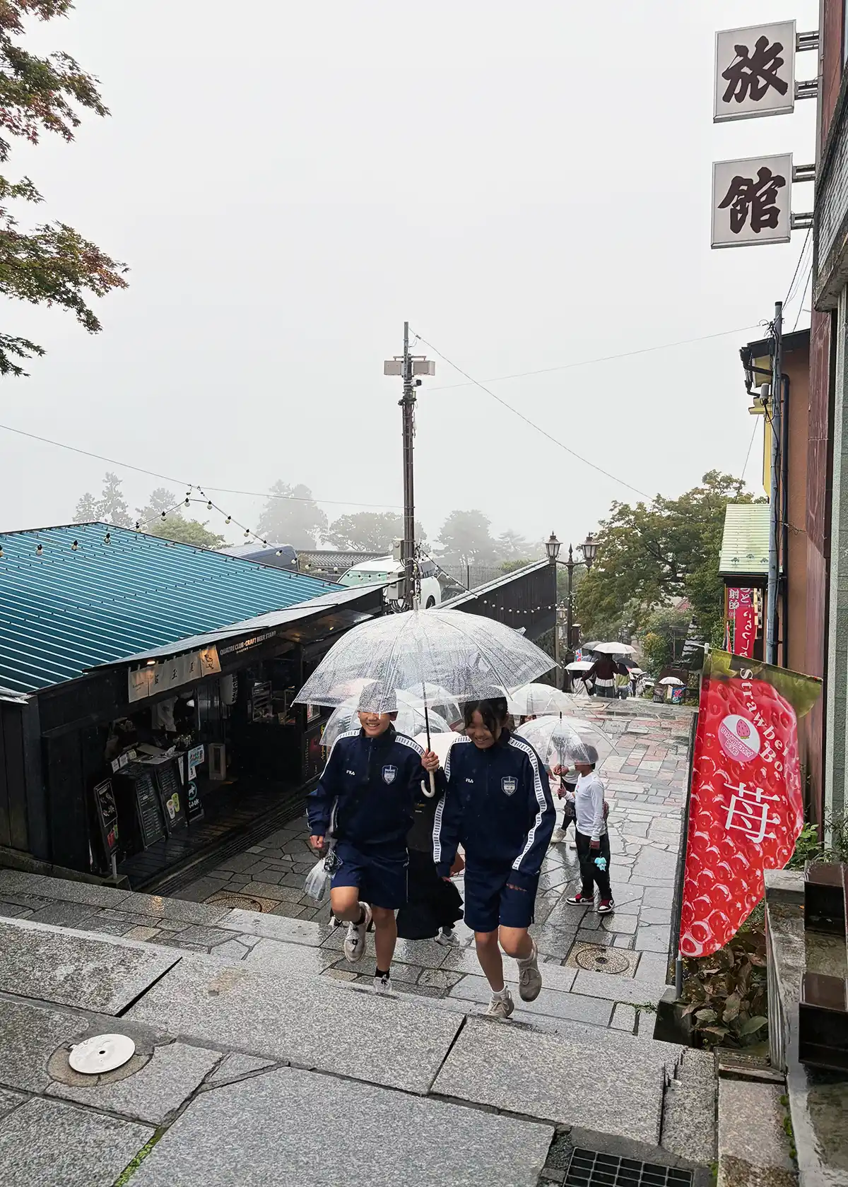 雨の伊香保温泉石段街。傘を差して石段を歩く観光客たち