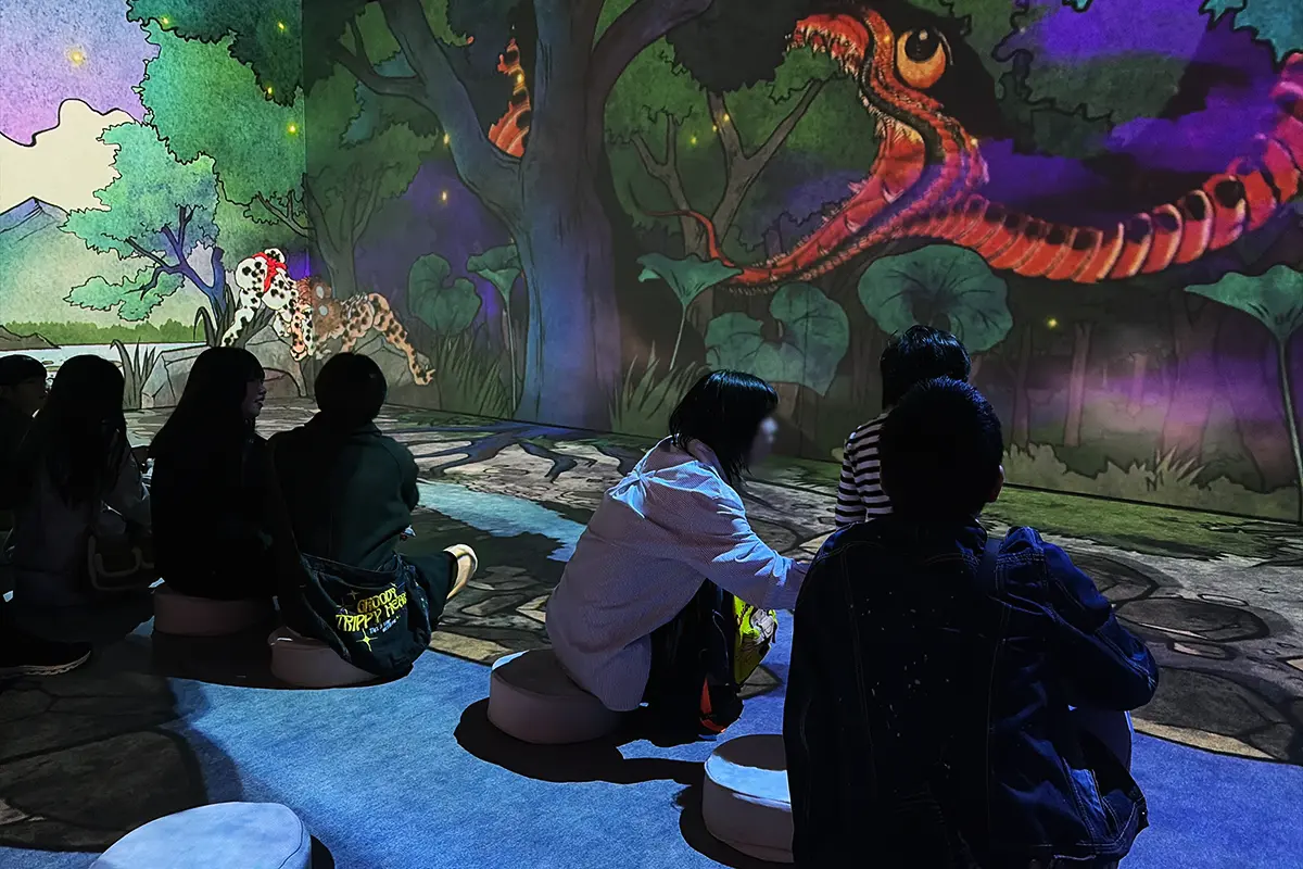 森の中を巨大な蛇が動き回る没入型シアターを楽しむ来場者の様子