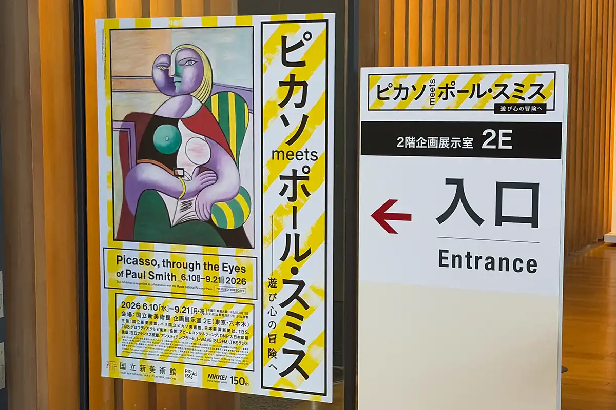 国立新美術館で開催された「ピカソ meets ポール・スミス」展の2階企画展示室の看板と、黄色いストライプが目を引く展覧会公式ポスターの入り口案内