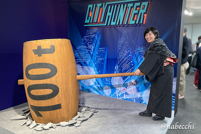 シティーハンター展の100tハンマーを持ち、楽しそうに構えるデニム着物姿の筆者