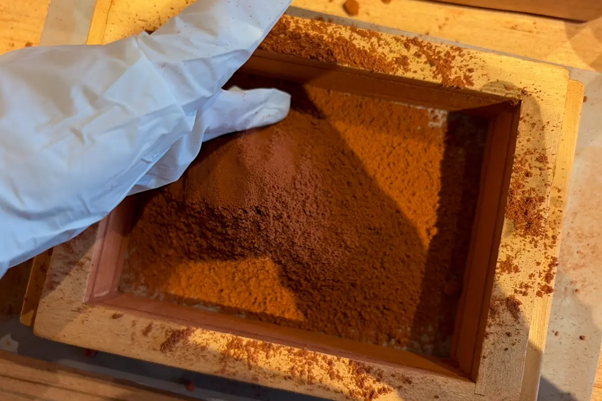 鋳型の上から砂をかけて型を覆う作業