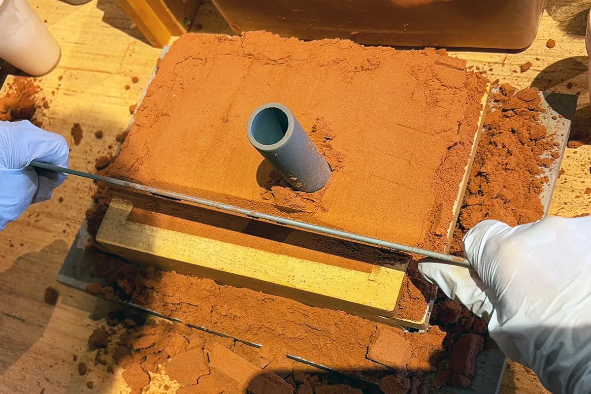 鉄の定規のようなものを両手で持ち、木枠の上部をすべらせて、平らにする