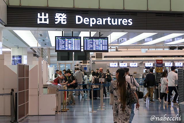 羽田空港の出発ロビーでチェックインを行う旅行客たち